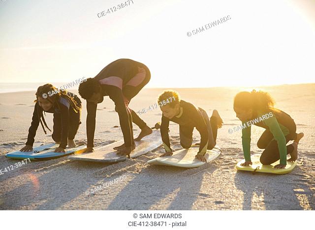 Father surfer teaching children surfing on surfboard on sunny summer beach