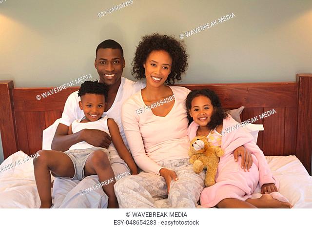 Happy African American family relaxing on bed and looking at camera