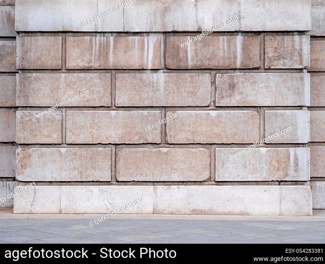 Dirty white cement blocks with concrete slabs and a curb on floor. Abstract empty urban interior background with gray brick wall and concrete floor tiling