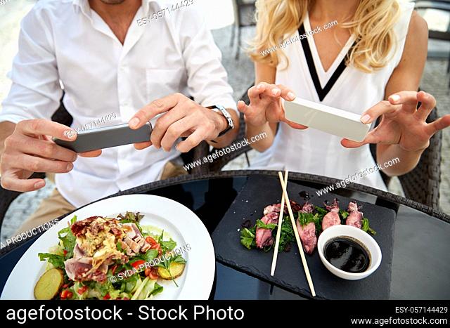 couple with smatphones photographing food