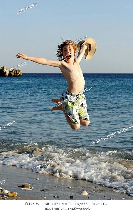 Boy jumping for joy on a beach by the sea