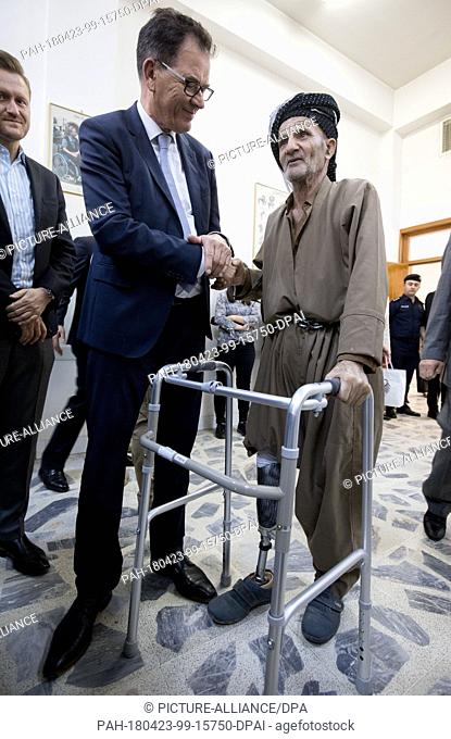 23 April 2018, Iraq, Dohuk: Minister for Development of the Christian Social Union of Bavaria (CSU), Gerd Mueller (L), speaking to a man with an artifical limb...