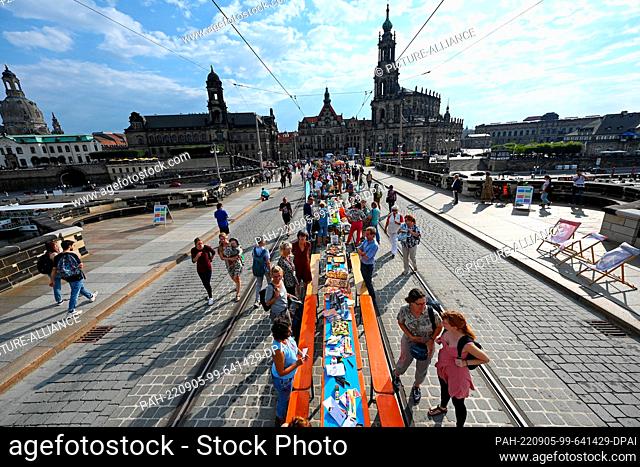 05 September 2022, Saxony, Dresden: Participants in the event ""Gastmahl für alle"" under the motto ""Dresden is(s)t bunt"", are on the Augustusbrücke