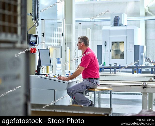 Engineer sitting and using computer in production factory