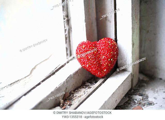 loneliness concept - red heart on white obsolete windowsill