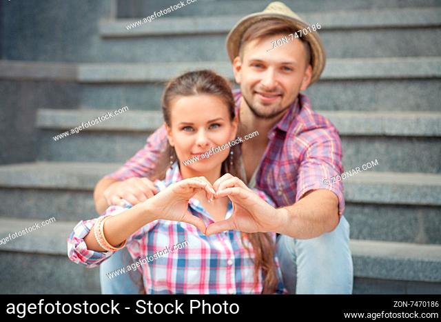 Portrait of young smiling people embracing tenderly and bonding. Man and woman making heart with their hands