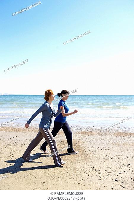 Two mature women exercising on beach