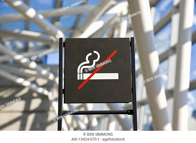 A detailed interior view shows a simple No Smoking sign amidst unique support joinery inside the spacious 60-meter high atrium's laminated-glass and steel...