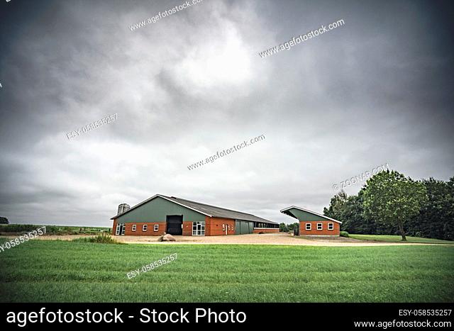 Farm under a cloudy sky with green fields waiting for the rain