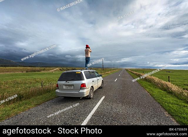 Guy with camera on car roof, Karamea, Buller District, West Coast, South Island, New Zealand, Oceania