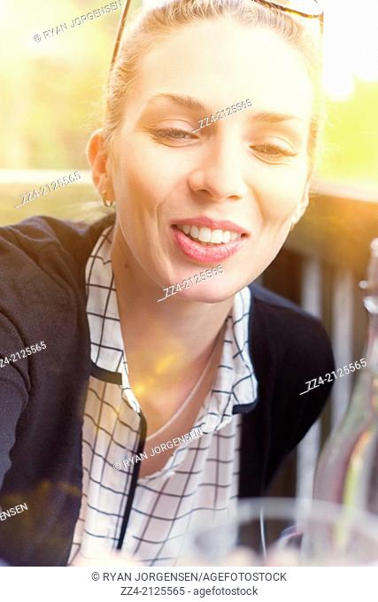Beautiful happy woman in candid and natural pose laughing with glass in hand when offering a toast of cheers for summer fun