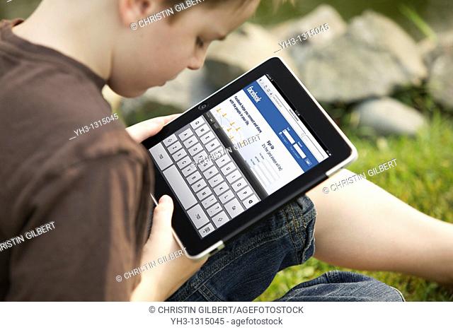 Young boy using an iPad to check his Facebook account