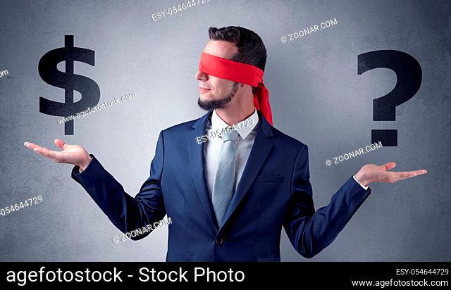 Serious businessmen standing in front of a grey wall with red ribbon on his eye, holding dollars
