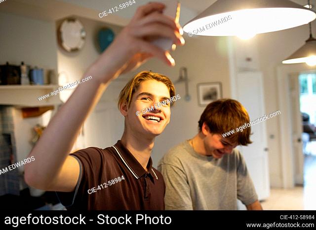Happy teenage boys taking selfie in kitchen