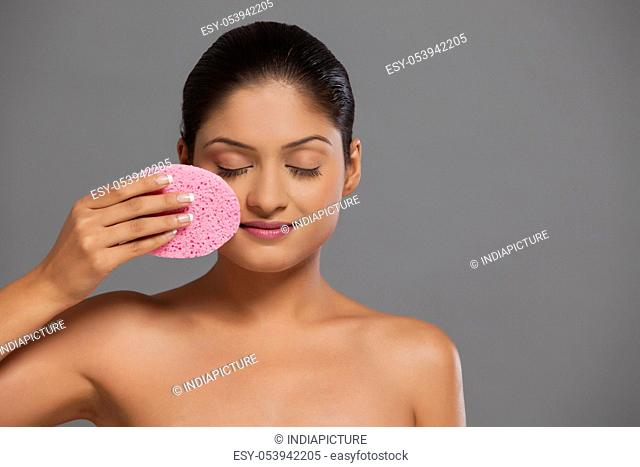 Close-up of woman using massage sponge on her face