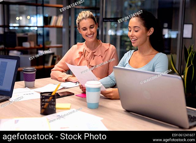 Smiling female advisors discussing over document while working at modern workplace