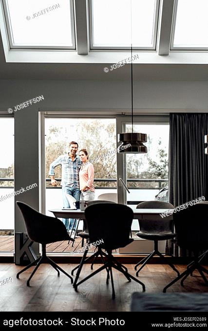 Mature couple standing in balcony at apartment