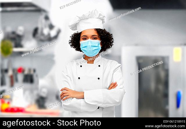 female chef in medical mask and toque in kitchen
