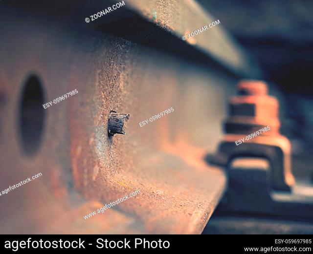 Selective field of focus. Detail of rusty screws and nut on old railroad track. Concrete tie with rusty nuts and bolts. Damaged surface of rail rod
