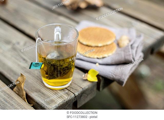 A cup of tea and syrup waffles on a wooden table in a garden