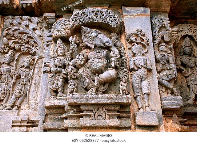 Ornate wall panel reliefs depicting from left Kamdev and his wife Rati, and dancing Ganesha. Kedareshwara temple, Halebidu, Karnataka, India