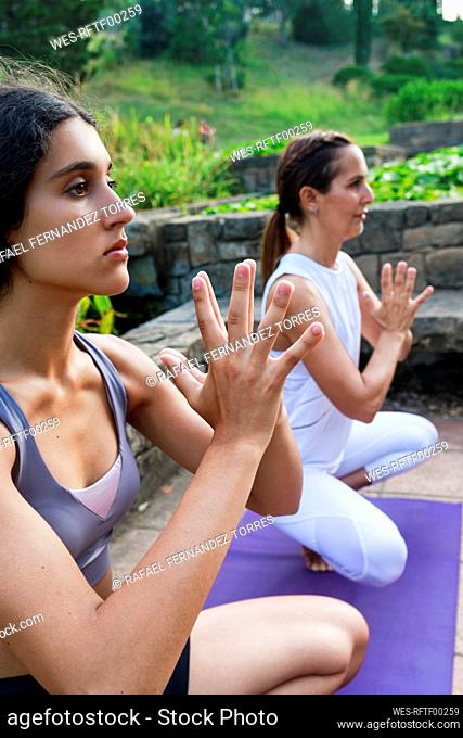 Teenage girl with hands clasped exercising with instructor at park