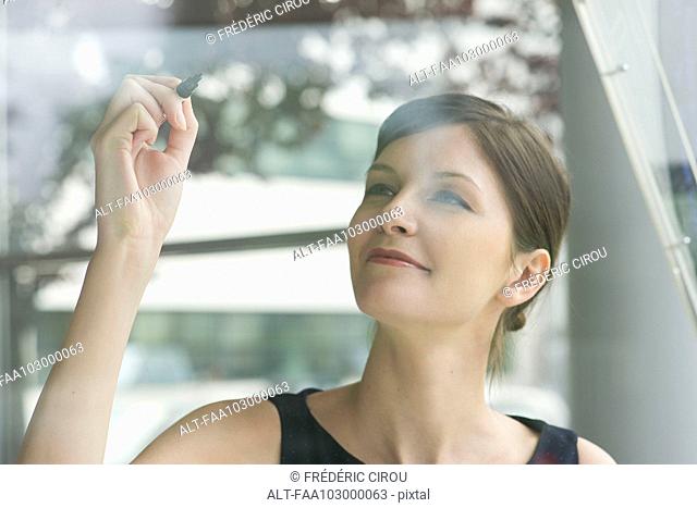 Woman preparing to write on window with marker