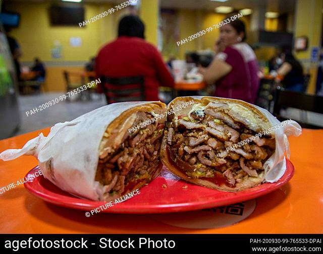 27 September 2020, Mexico, Mexiko-Stadt: A large sandwich with pieces of schnitzel, sauces and cheese is placed on a table in a snack bar