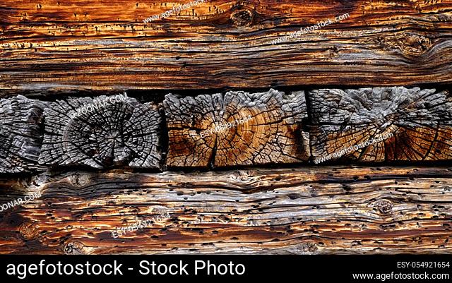 Wettergegerbte braune Holzbalken eines alpinen Hauses. Querformat. Weathered brown wooden beams of an alpine house. Horizontal format