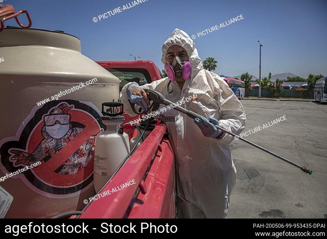 dpatop - 02 May 2020, Mexico, Tijuana: A member of the group ""Covid Busters"" is standing in a protective suit next to the car with the group's logo on the...