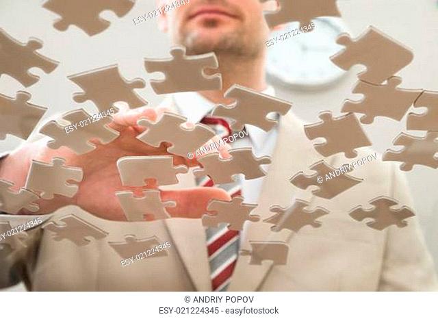 Businessman Separating Jigsaw Puzzle On Glass Table