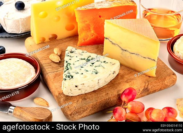 Cheese platter. Blue cheese, red Leicester, Brie, Emmental and others with wine and grapes on a white background