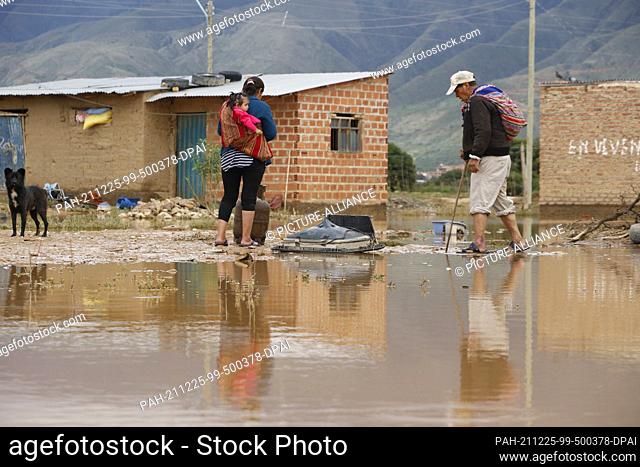 24 December 2021, Bolivia, Cochabamba: Don Fidel Vega walks through the water in the area of the ""barrios unidos"" in the province of Cliza