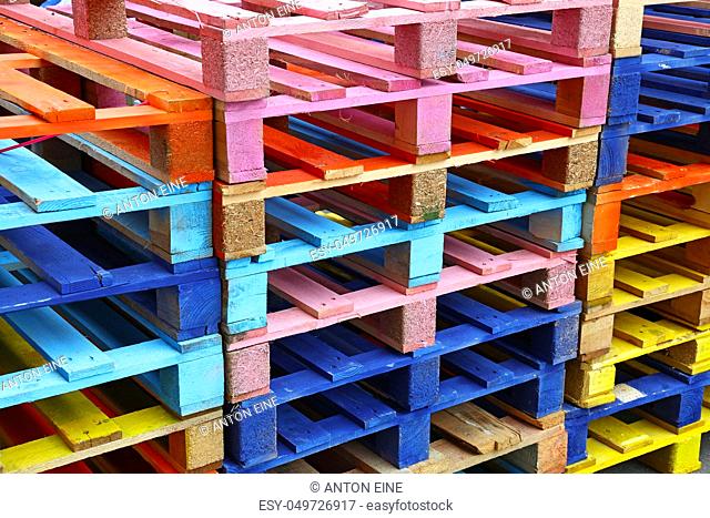 Close up stack of many vivid multicolor painted colorful wooden pallets, high angle diagonal view