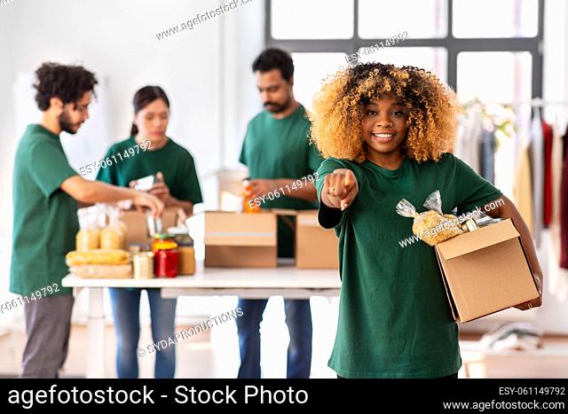 female volunteer with food in box points to camera