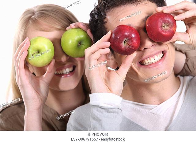 Couple holding up apples to their eyes
