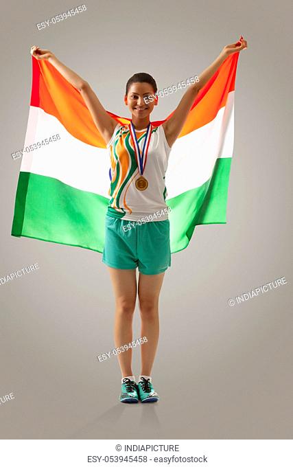 Full length of female medalist celebrating victory with Indian flag against gray background