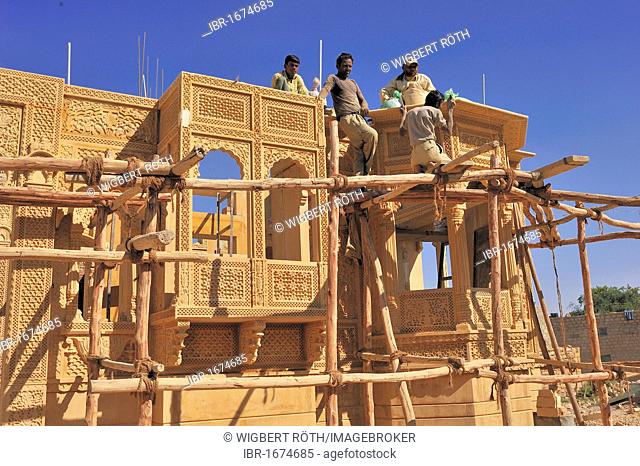 Craftsmen working on a simple wooden frame with knotted ropes on an ornate sandstone facade, Jaisalmer, Rajasthan, India, Asia