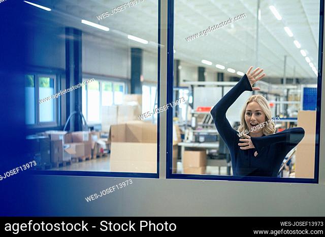Surprised businesswoman leaning on glass window in industry