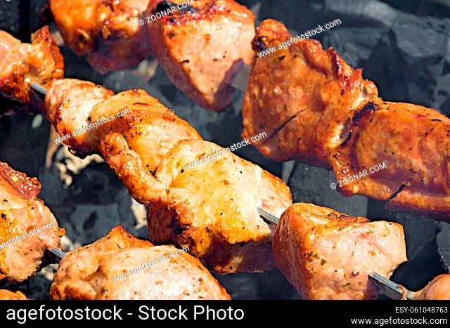 Shashlik of pork meat on the coals in the smoke. Closeup. Shooting on a sunny day