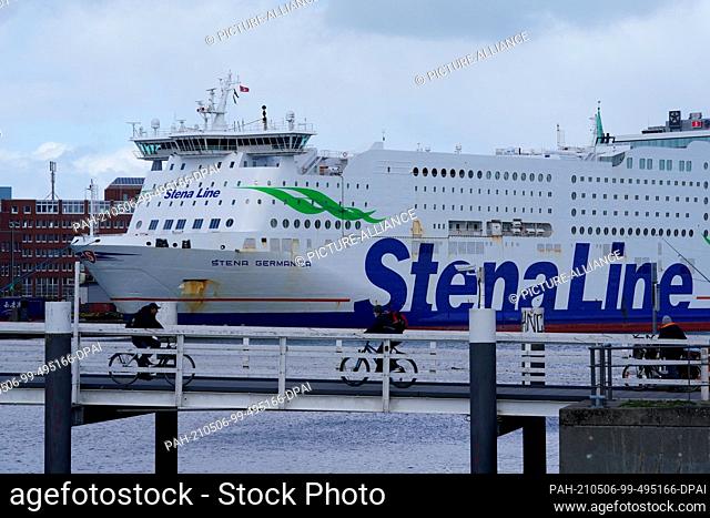 06 May 2021, Schleswig-Holstein, Kiel: Passers-by ride a bicycle over the Hörn Bridge. In the background a Stena Line ferry lies at the quay
