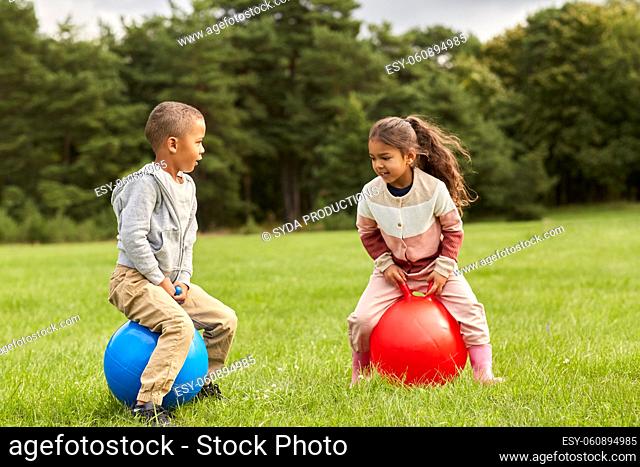 happy children bouncing on hopper balls at park