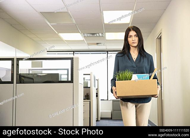 A young female employee carrying office possessions after being laid off