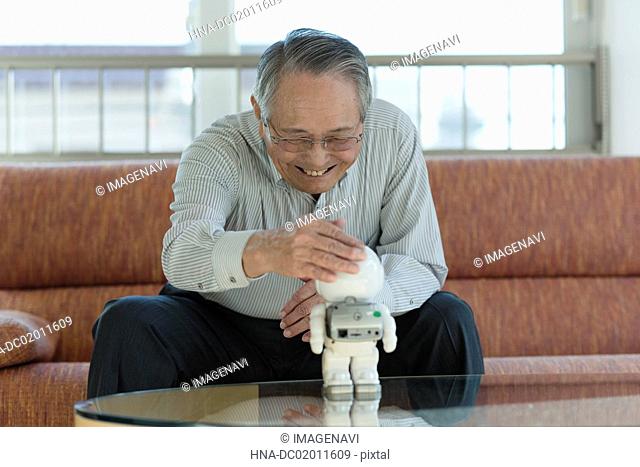 Senior man playing with robot