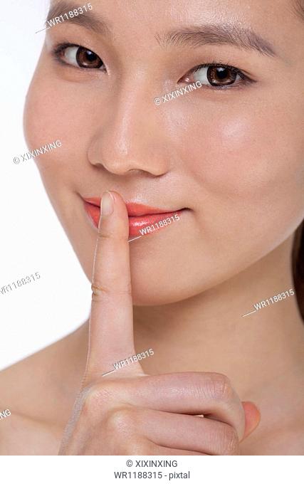 Young beautiful woman with her hands on her lips, looking at camera, studio shot
