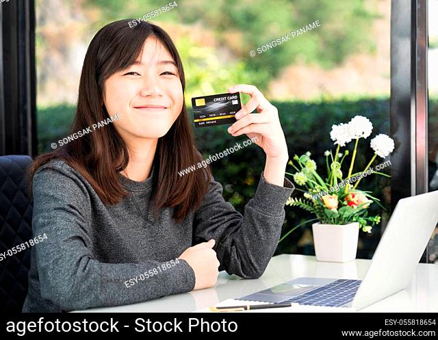 Young woman holding credit card with laptop computer on deck. Online shopping concept