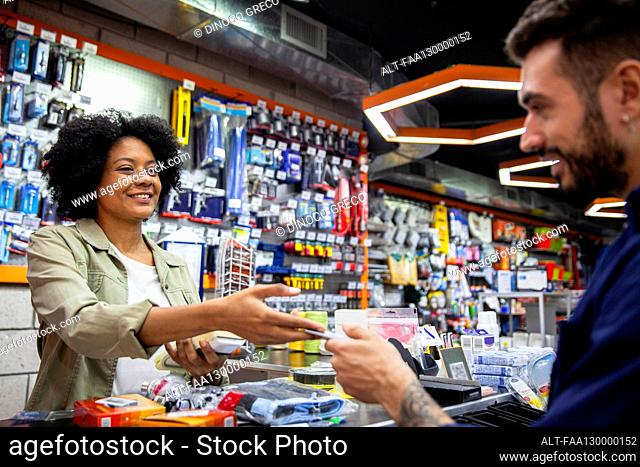 African American hardware shop worker charging on credit card to customer
