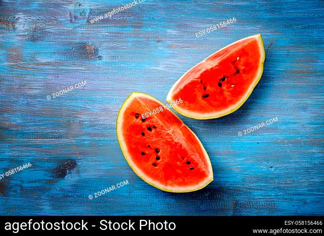Slices of ripe watermelon on a blue wooden countertop