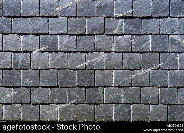 The street wall of the house is revetted with square plates of a black fragile stone