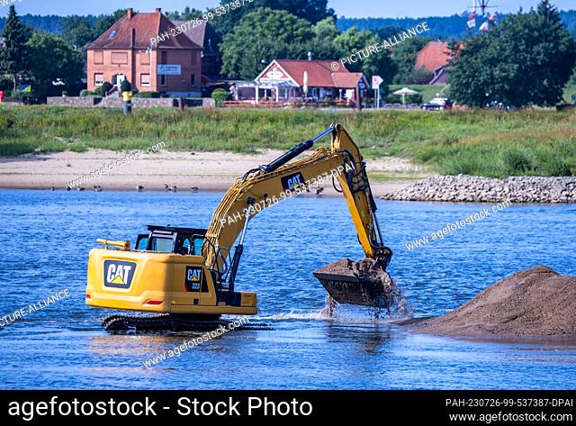 26 July 2023, Lower Saxony, Neu Bleckede: An excavator is used to deepen the access road to the Elbe ferry pier. A sandbank and low water prevent the operation...